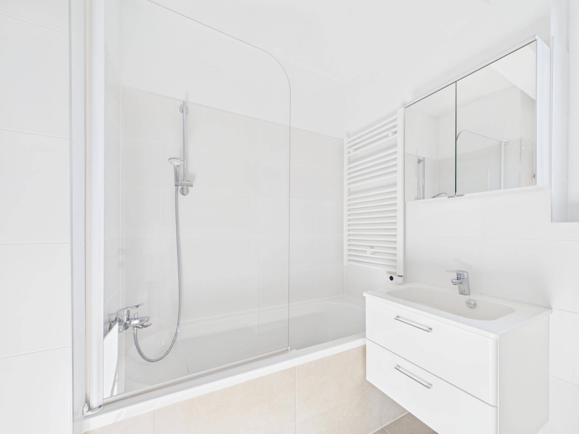 Modernes Badezimmer mit Badewanne, Duschfunktion, Waschbecken und beheiztem Handtuchhalter.