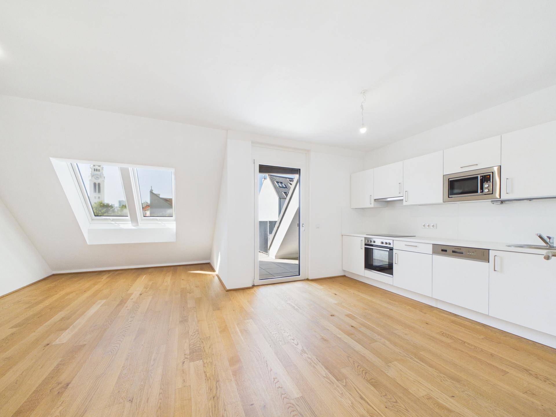 Offener Wohn- und Küchenbereich mit Holzboden, Dachfenster und direktem Terrassenzugang.