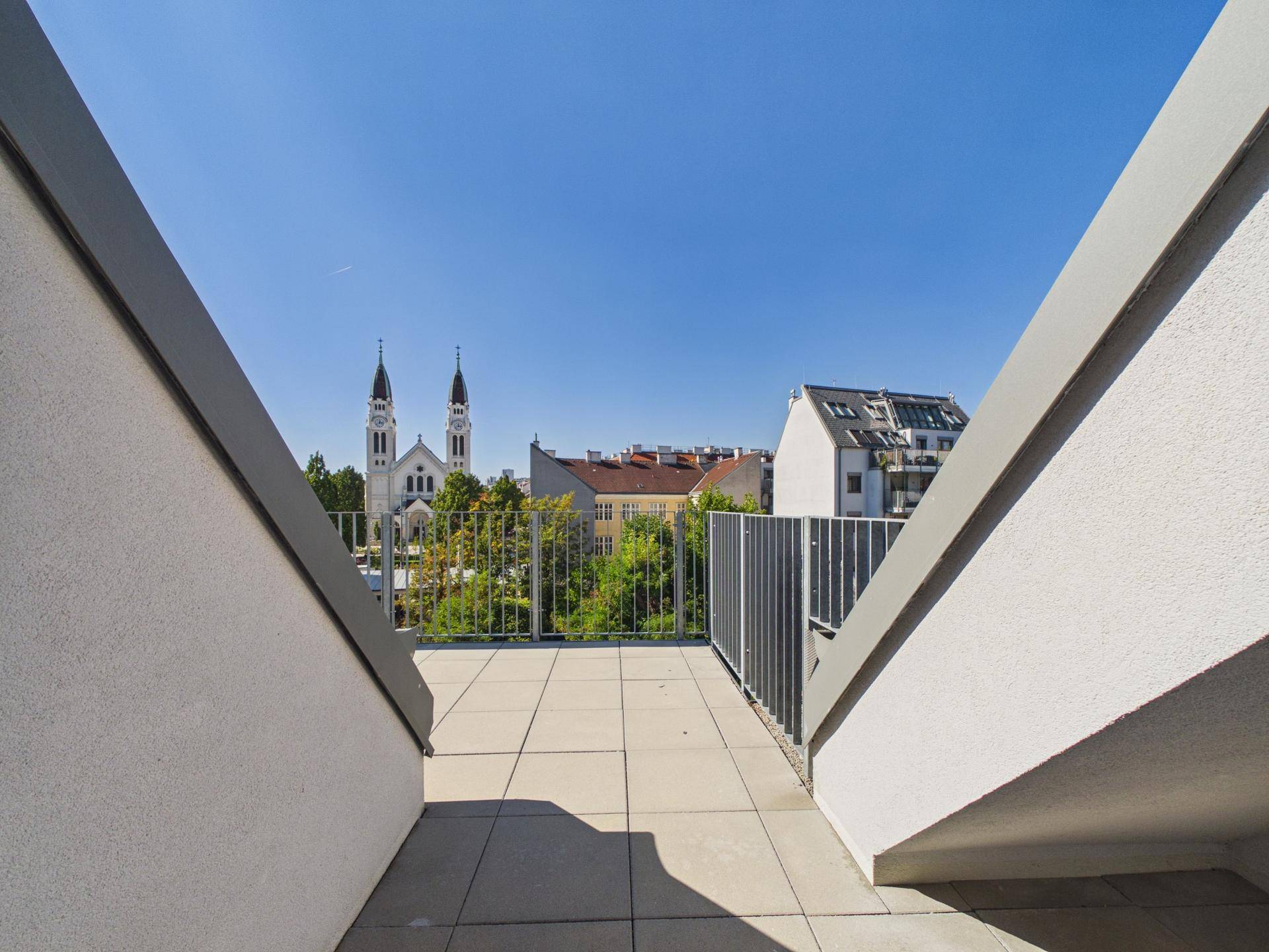 Panoramablick von der Dachterrasse auf die Stadtkulisse mit einer markanten Kirche.