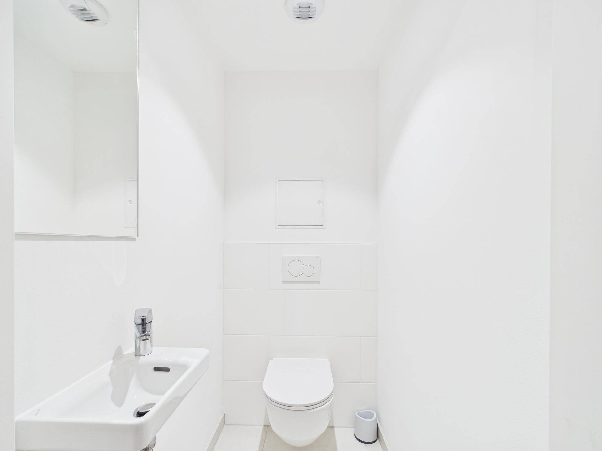 Kleines, helles Gäste-WC mit wandhängender Toilette und kompaktem Waschbecken.