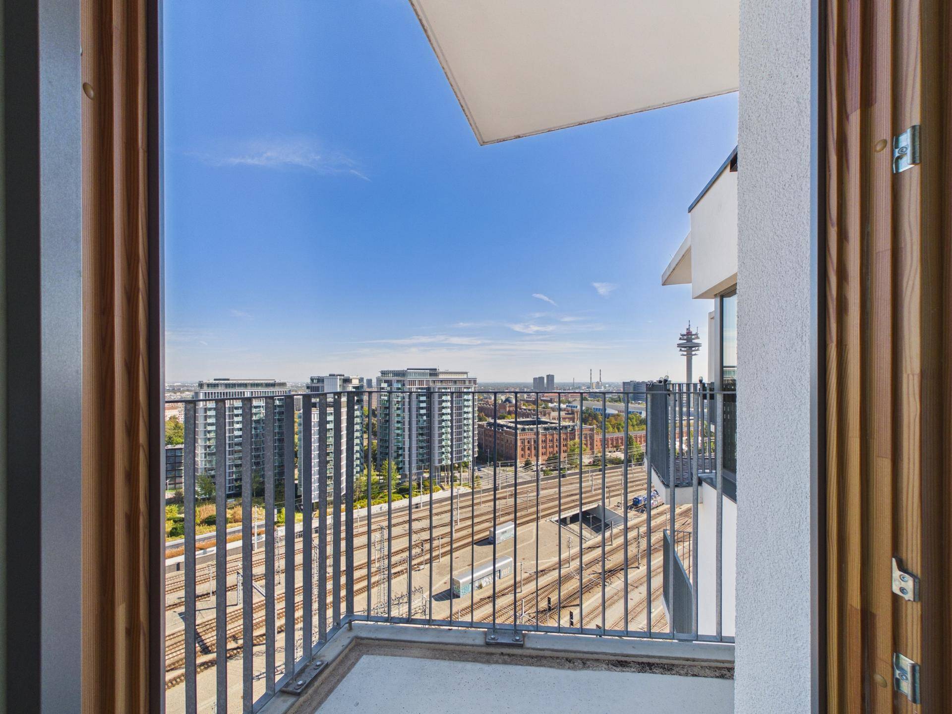 Geräumiger Balkon mit Panoramablick auf die Stadt, Bahngleise und den Fernsehturm.