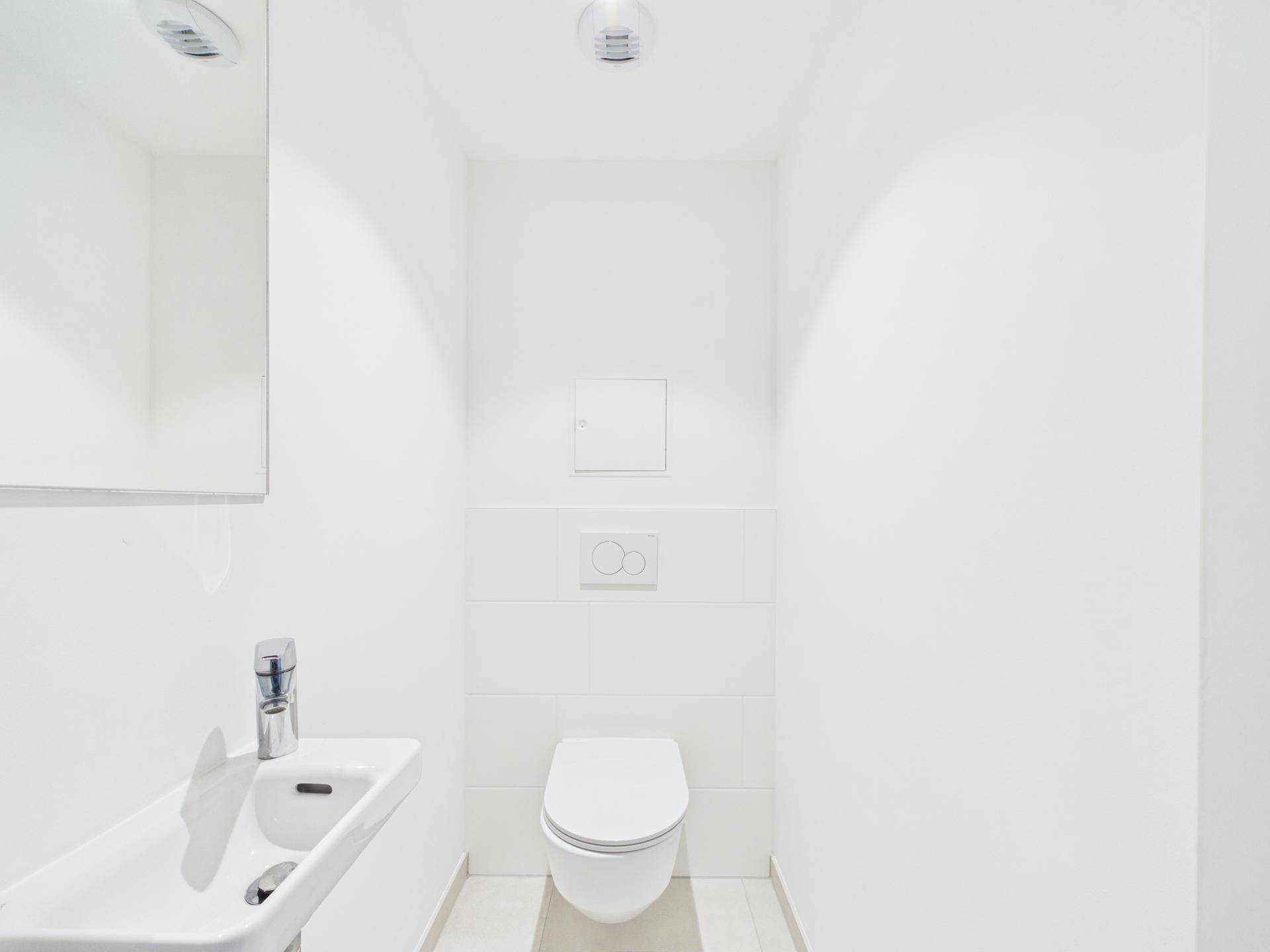 Kleines, helles Gäste-WC mit wandhängender Toilette und kompaktem Waschbecken.