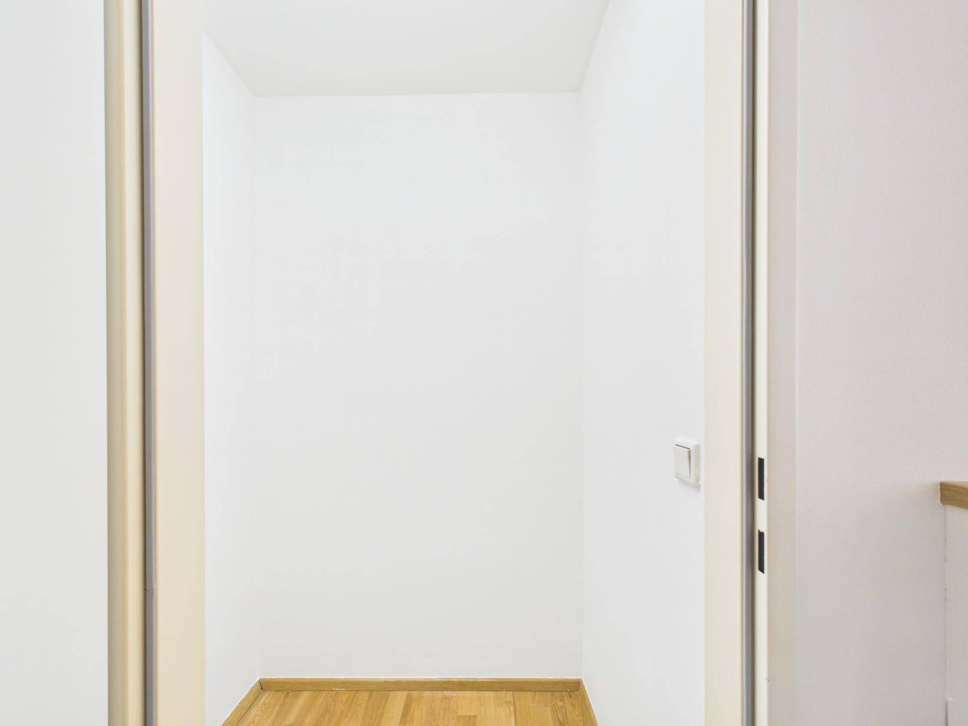 Praktischer Abstellraum mit Holzboden und weißen Wänden für zusätzlichen Stauraum.