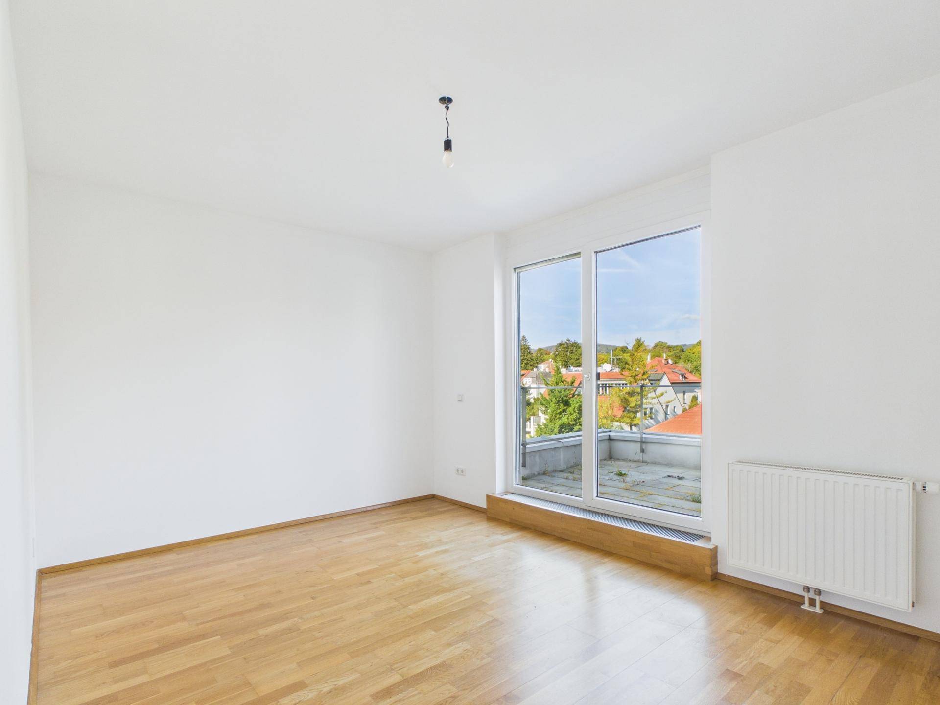 Geräumiges Zimmer mit Holzboden, großen Fenstern und Zugang zu einer Terrasse mit Weitblick.