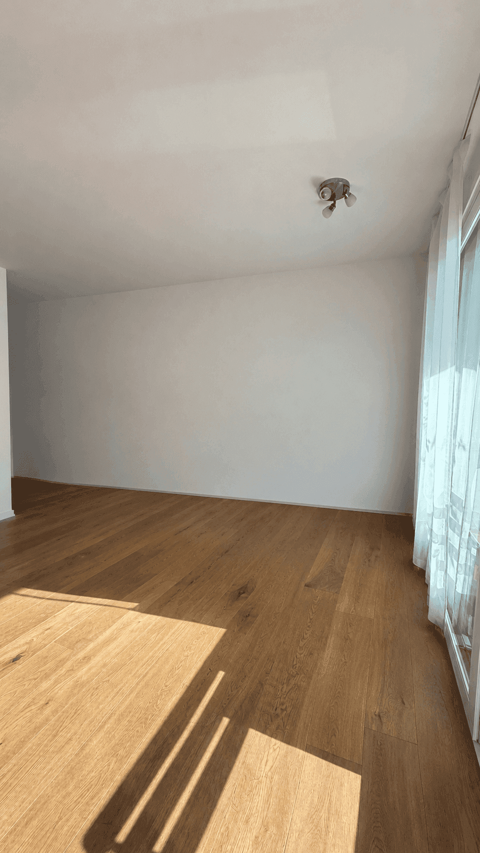 Helles Wohnzimmer mit Holzboden und viel natürlichem Licht, bereit zur individuellen Gestaltung.