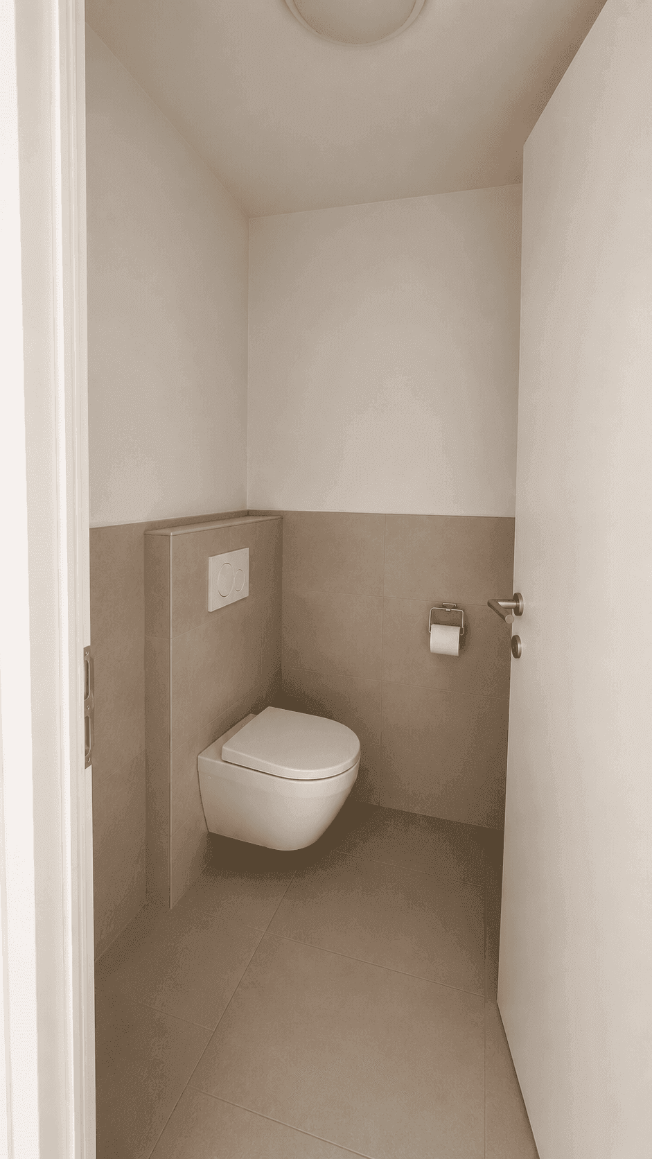 Separates Gäste-WC mit Wand-WC und modernen grauen Fliesen, sauber und funktional.