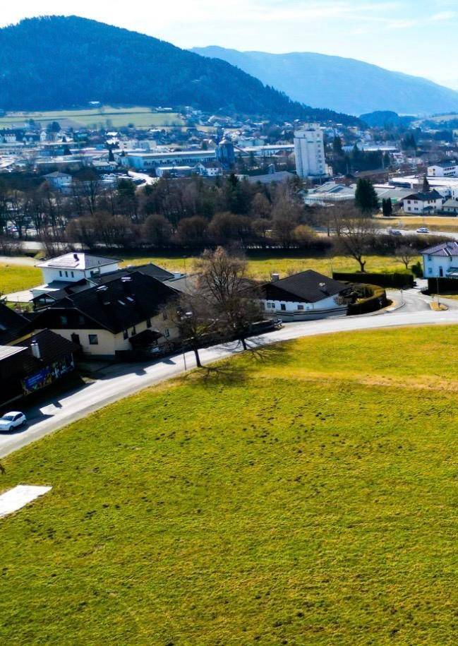 Weitläufiges grünes Grundstück mit Blick auf die umliegende Bebauung und die entfernten Berge.