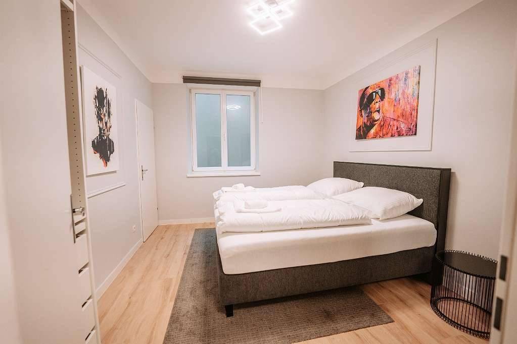 Helles Schlafzimmer mit Doppelbett, Teppich und einem Fenster für natürliches Licht.