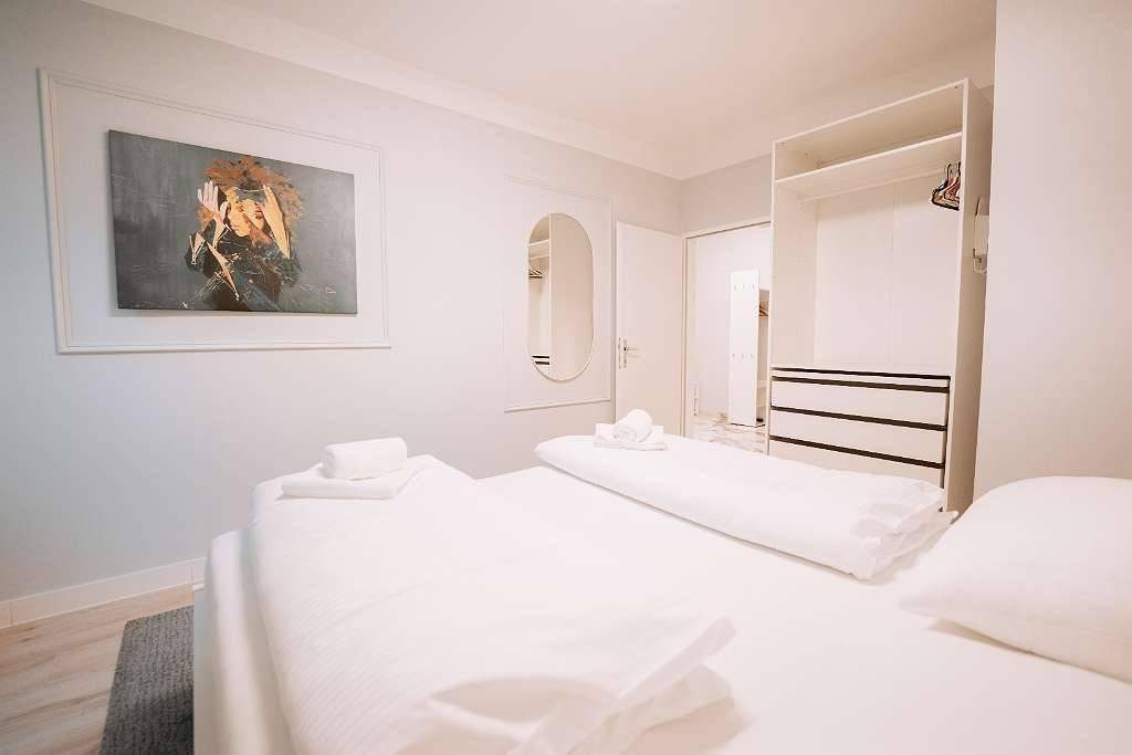 Schlafzimmer mit Doppelbett, Teppich und offenem Kleiderschrank für zusätzlichen Stauraum.
