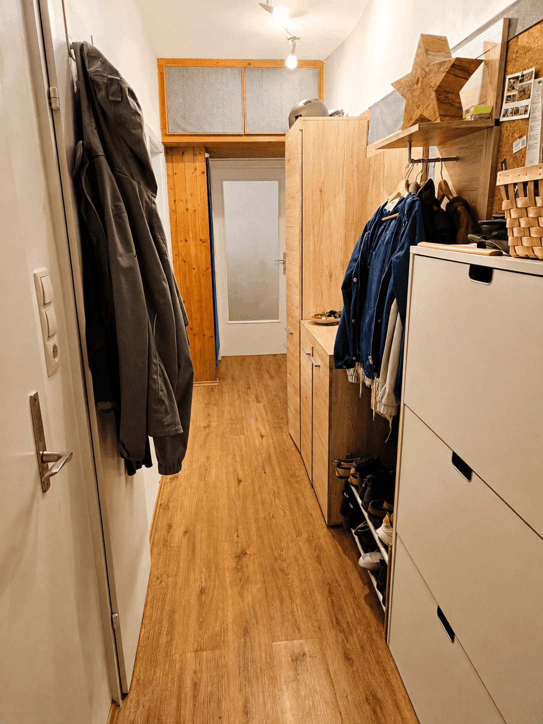 Langer Flur mit Holzoptikboden, Garderobe und praktischem Stauraum.