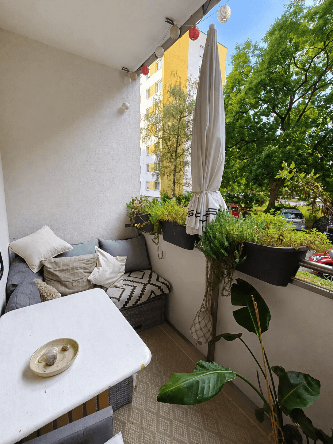 Gemütlicher Balkon mit Sitzgelegenheiten, Pflanzen und Blick auf die umliegende Bebauung und Bäume.
