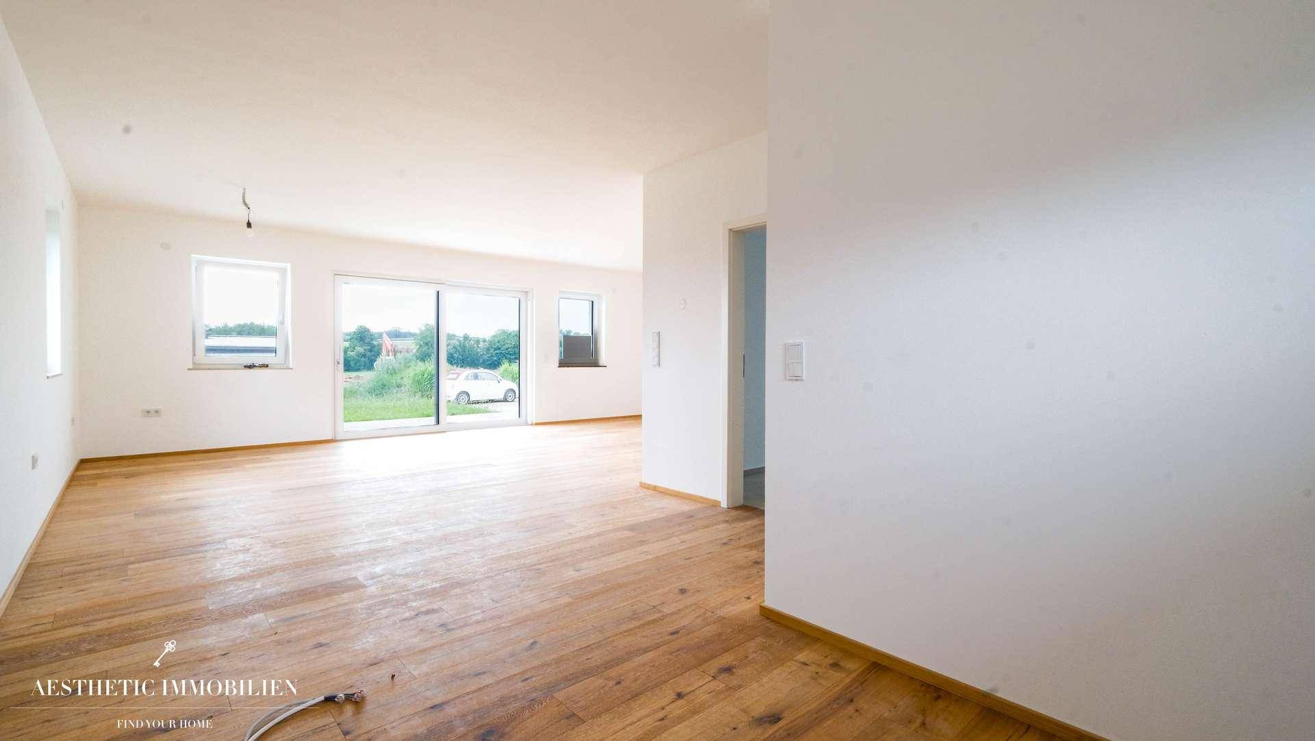 Großer, leerer Raum mit Holzboden und Schiebetüren, ideal für Wohn- und Essbereich.