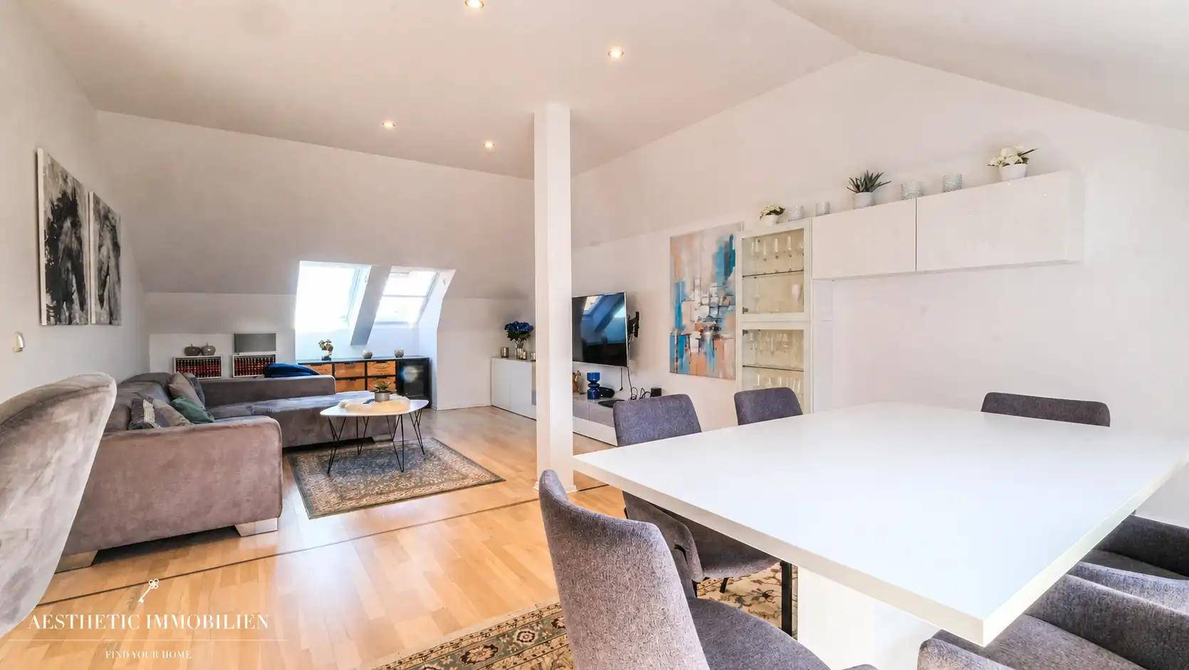 Offener Wohn-Essbereich im Dachgeschoss mit Holzboden, modernem Dekor und Dachfenster.
