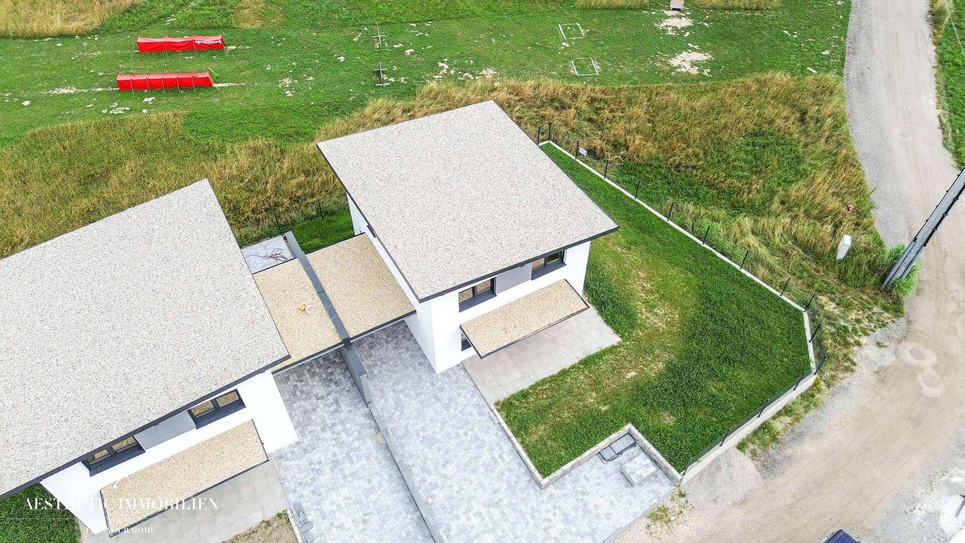Luftaufnahme einer modernen Doppelhaushälfte mit Garten und gepflasterter Zufahrt.
