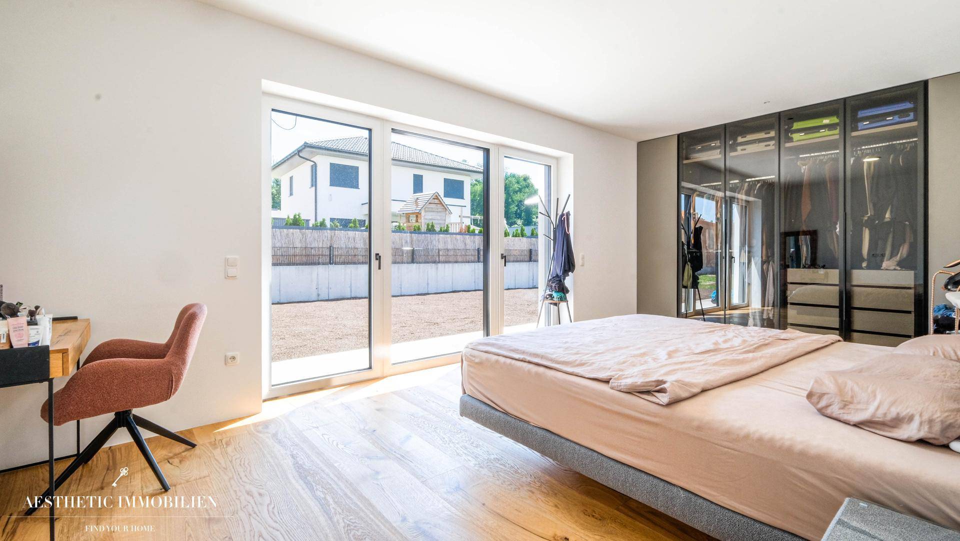 Helles Schlafzimmer mit Holzboden, großem Fenster und integriertem Kleiderschrank.