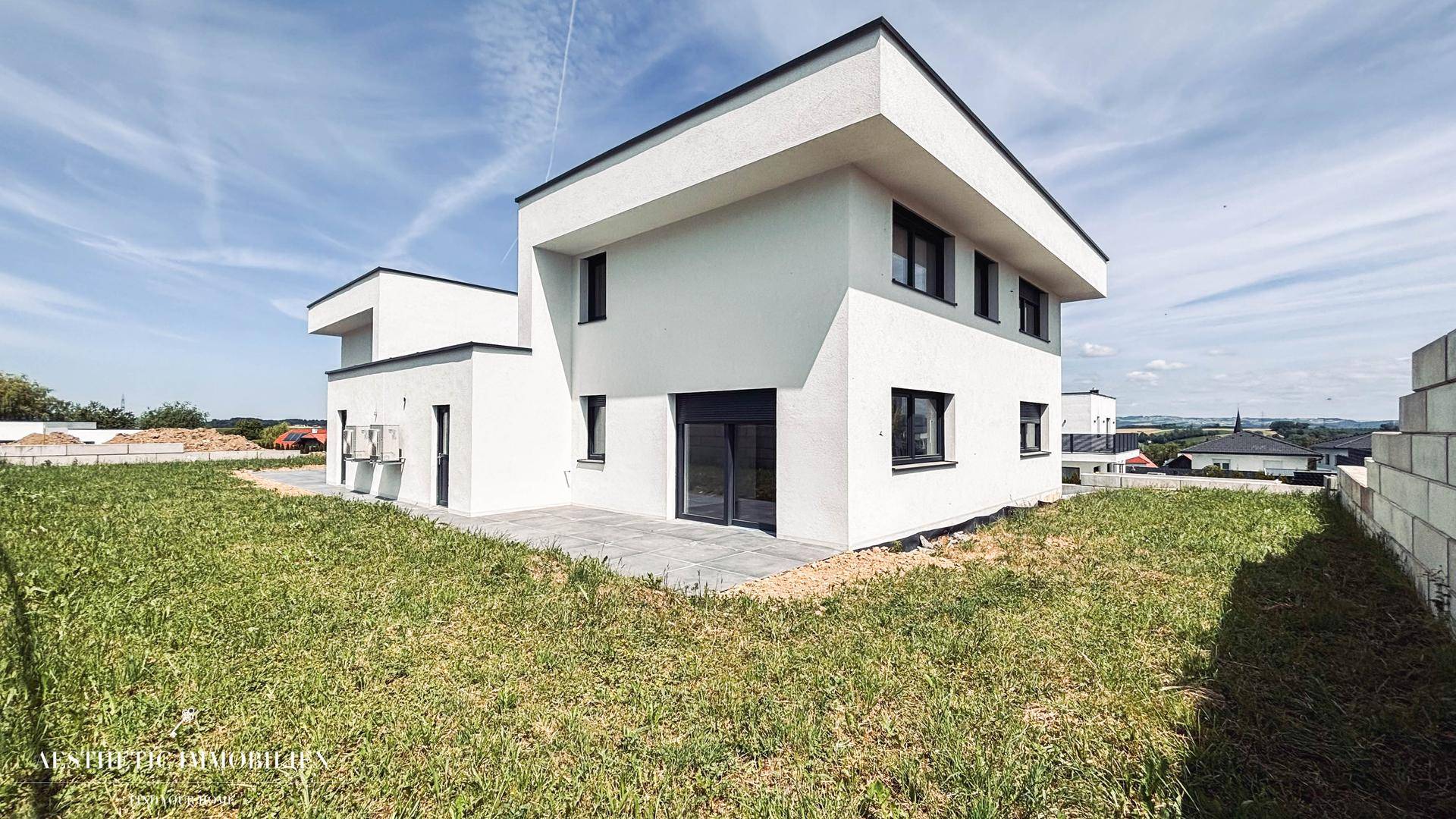 Neubau-Einfamilienhaus mit moderner Architektur und ungestaltetem Gartenbereich.