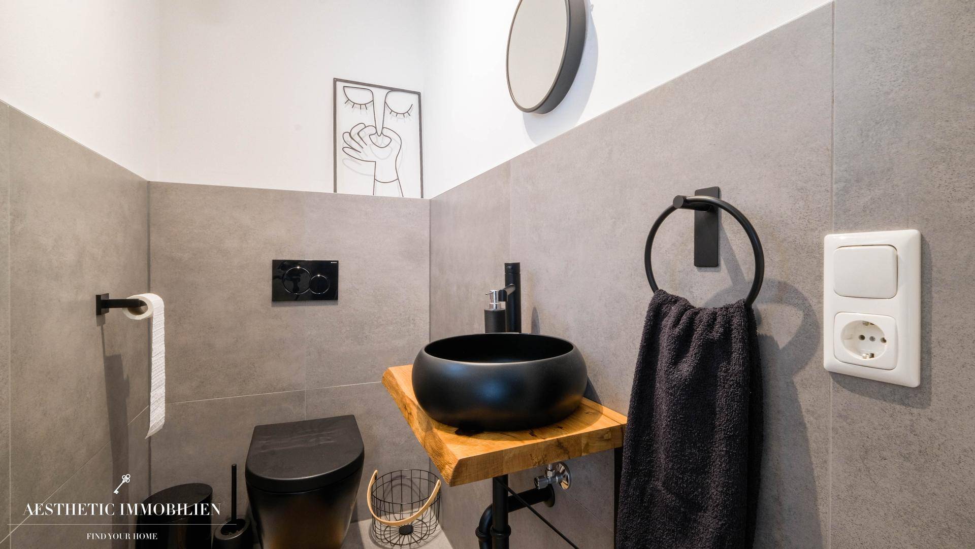 Modernes Gäste-WC mit schwarzen Armaturen, Wand-WC und stilvollem Waschbecken.