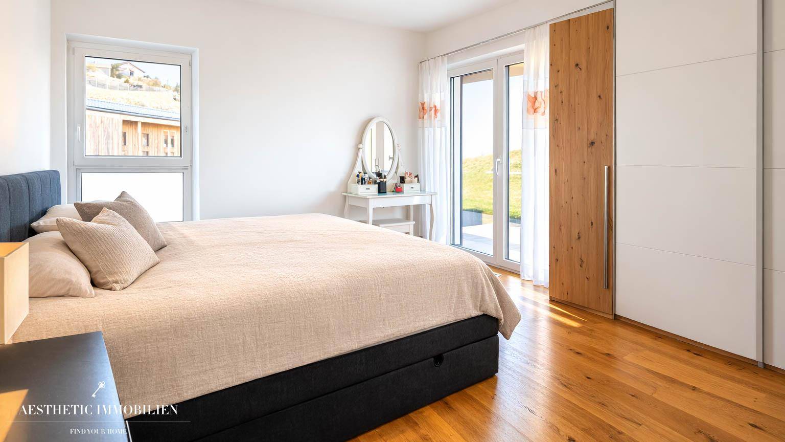 Gemütliches Schlafzimmer mit Holzboden, großem Fenster und integriertem Kleiderschrank.