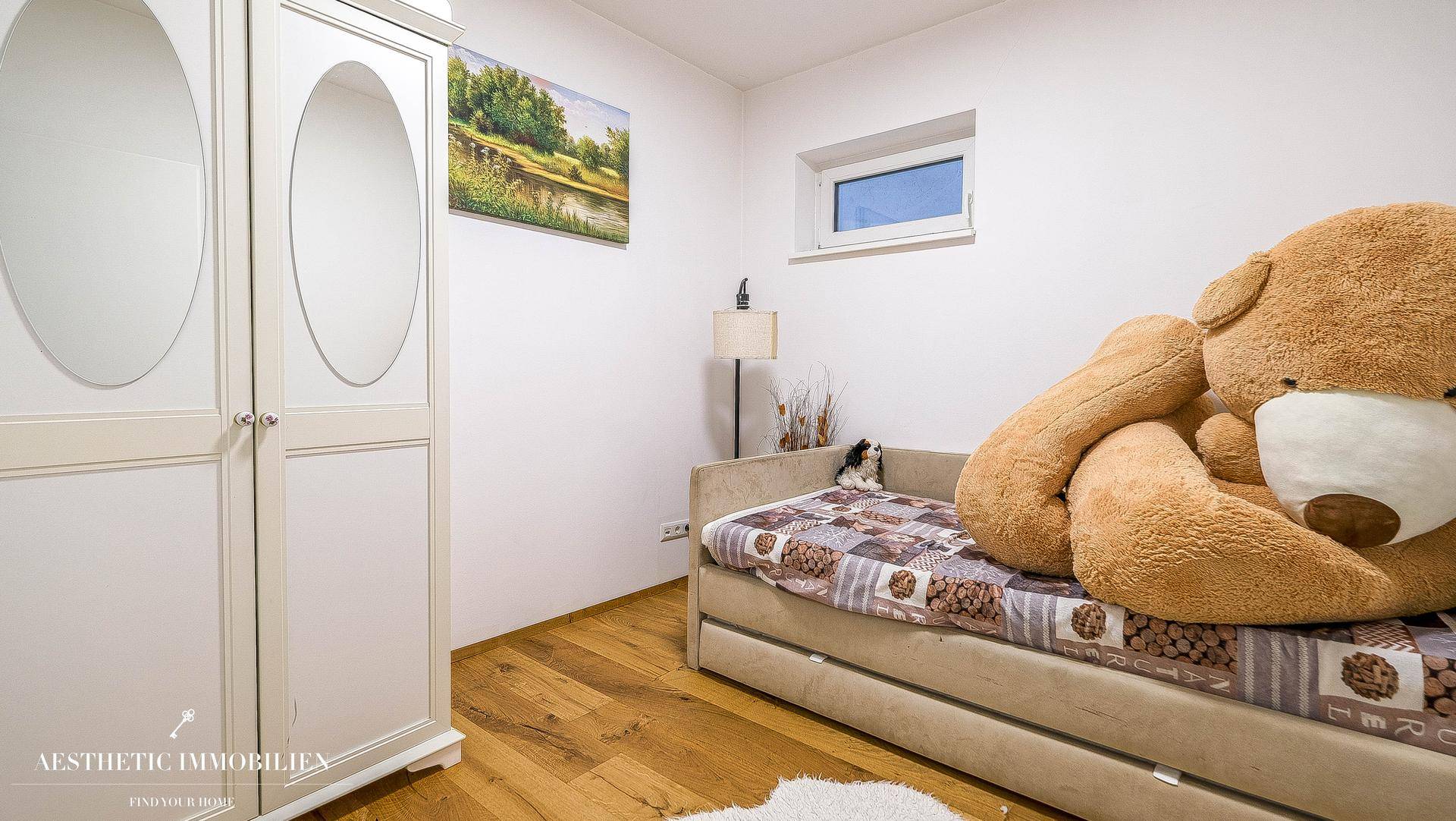 Kinderzimmer mit Einzelbett, Holzboden und großem Plüschtier.