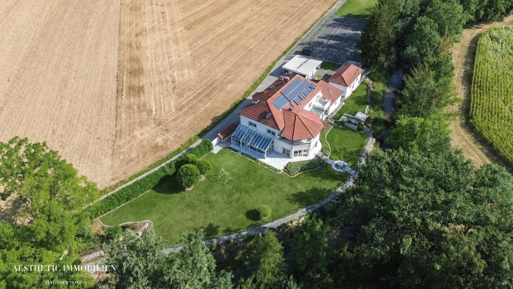 Luftaufnahme des weitläufigen Grundstücks mit Garten, Spielplatz und angrenzenden Feldern.