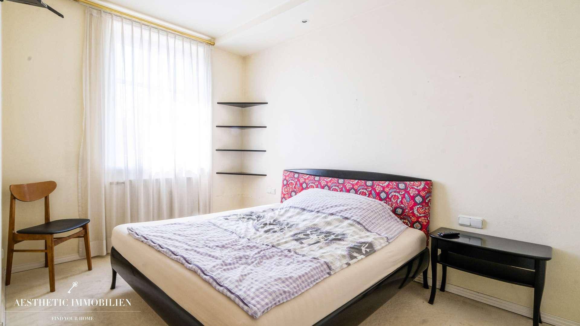 Schlafzimmer mit Doppelbett, Teppichboden und schlichten Wandregalen.