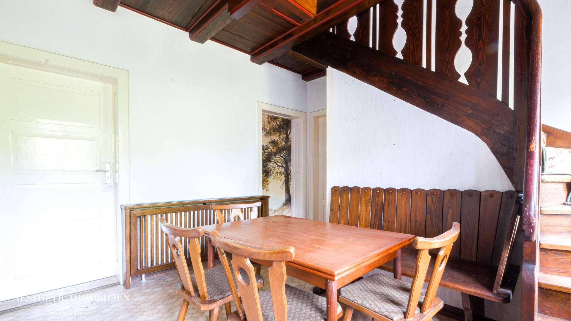 Gemütlicher Essbereich mit Holztisch, Bank und Zugang zu einer weiteren Etage.