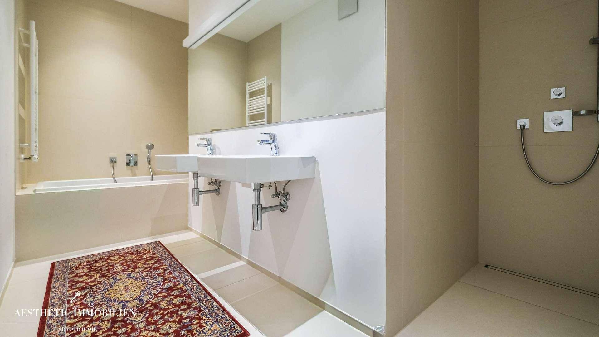 Elegantes Badezimmer mit Badewanne, separater Dusche, Doppelwaschbecken und einem großen Wandspiegel.