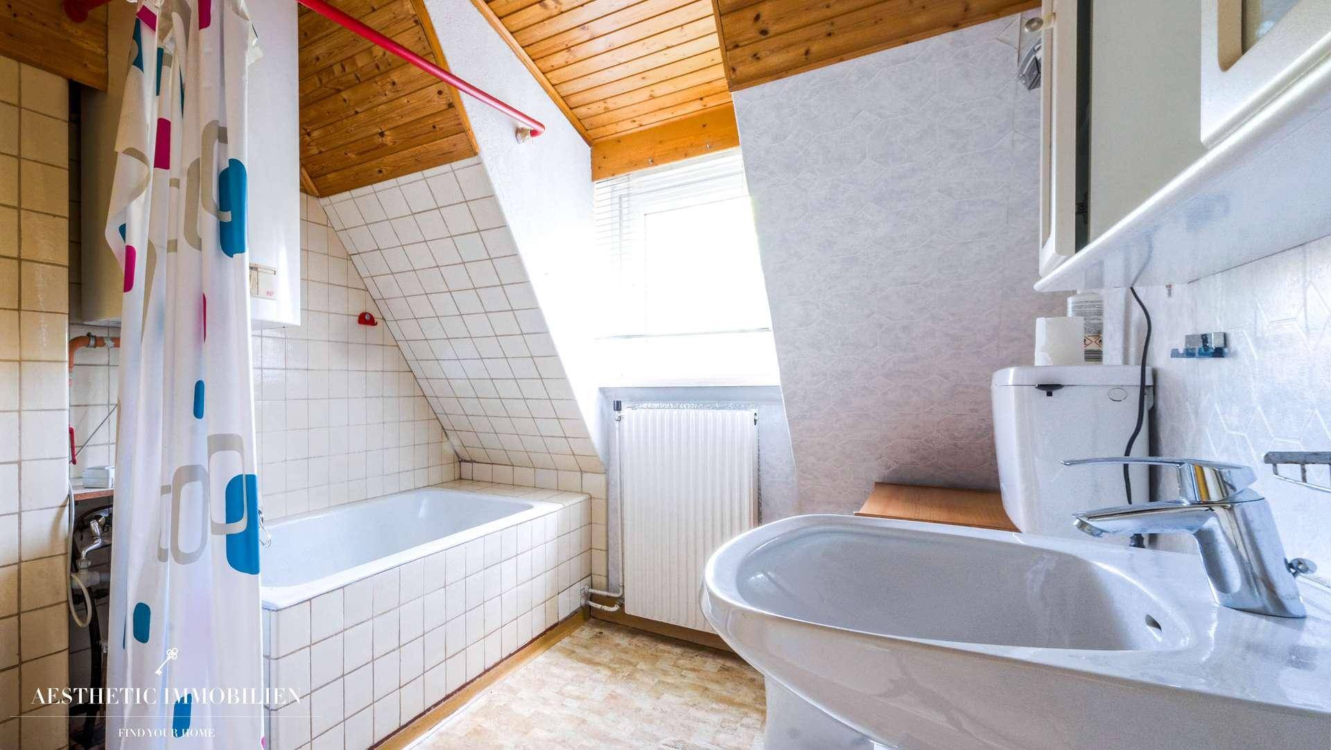Helles Badezimmer im Dachgeschoss mit Badewanne, WC und Fenster.