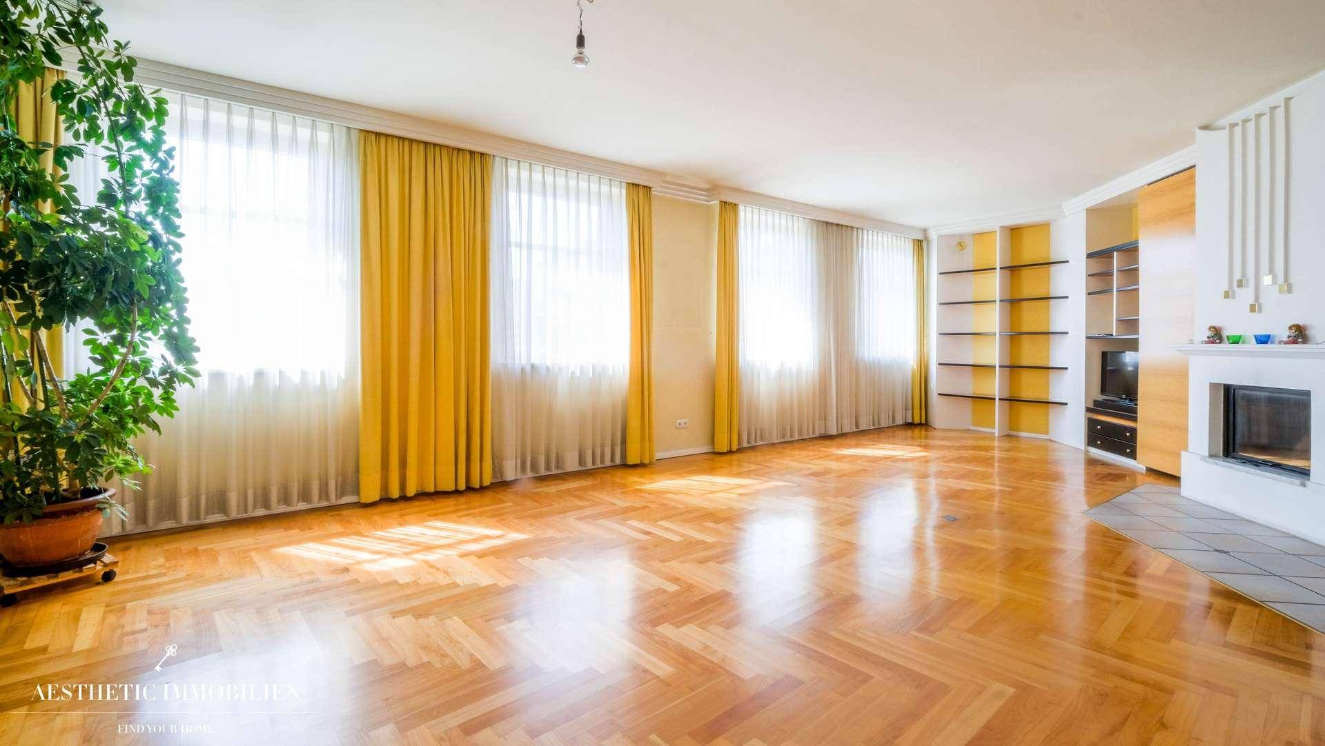 Großzügiges, leeres Wohnzimmer mit Fischgrätparkett, Kamin und Einbauregalen.