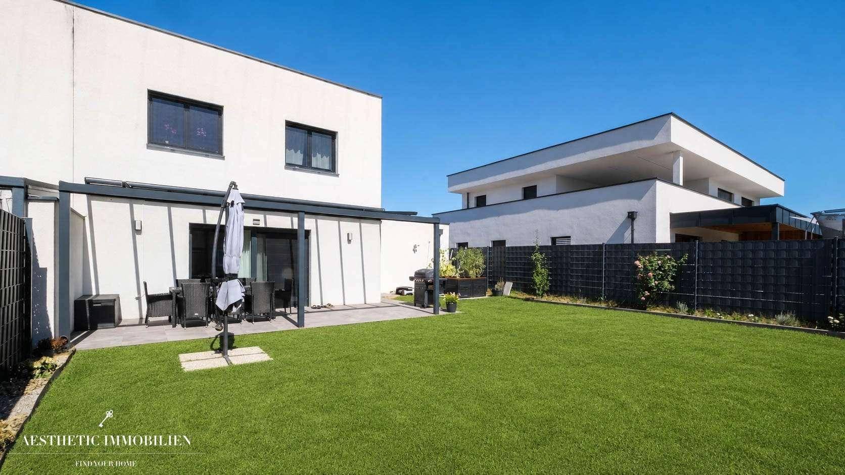 Großer, gepflegter Garten mit Rasenfläche und überdachter Terrasse am Haus.