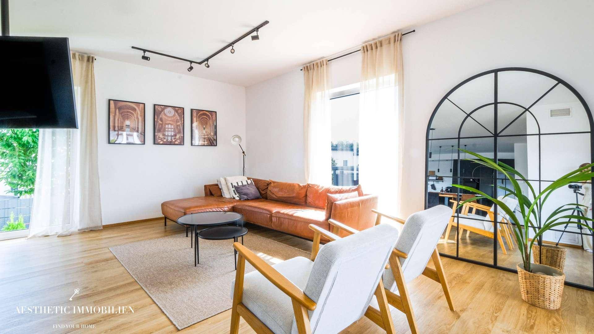 Helles Wohnzimmer mit bequemer Ledercouch, Holzboden und großem Bogenfensterspiegel.