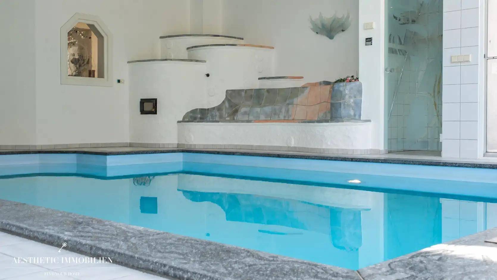 Detailansicht des Innenpools mit Kachelofen und gefliestem Beckenrand in einem luxuriösen Ambiente.