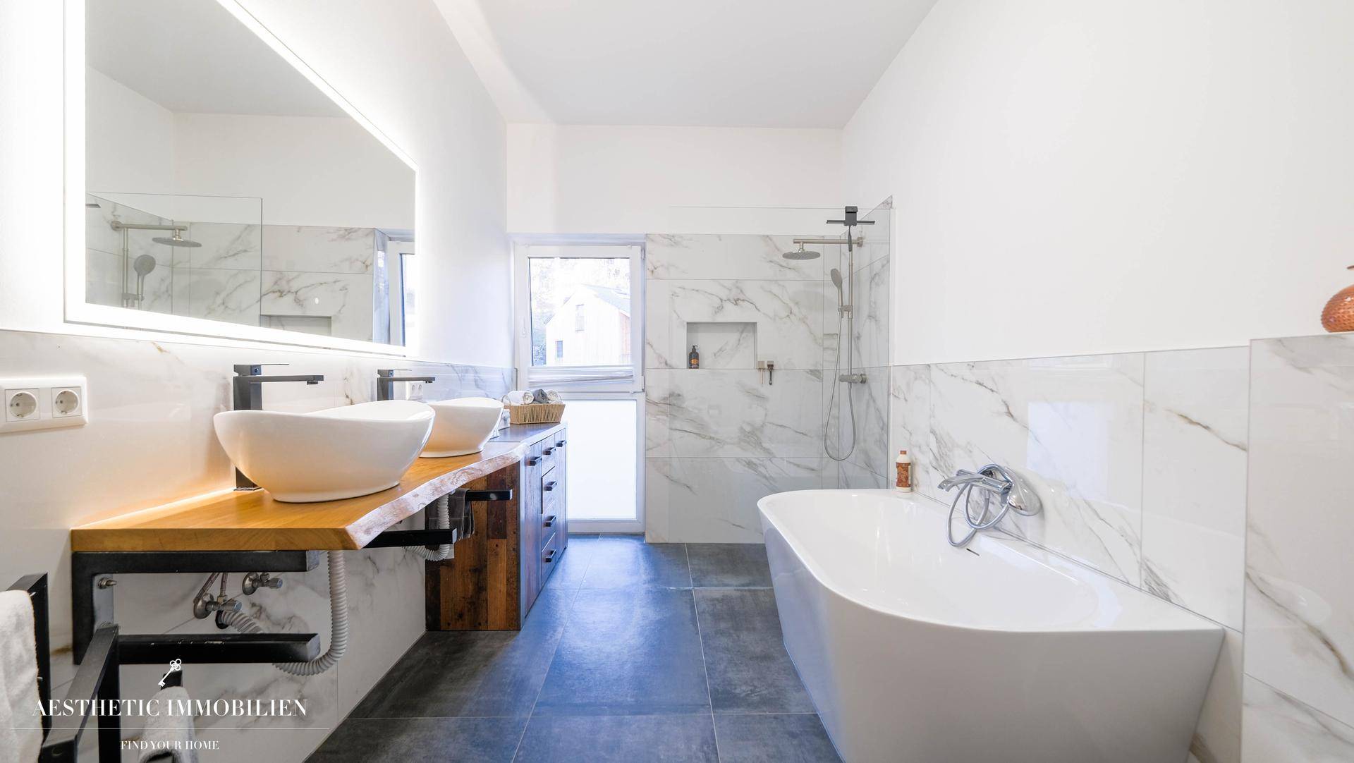 Modernes Badezimmer mit freistehender Badewanne, Doppelwaschbecken und Marmorfliesen.