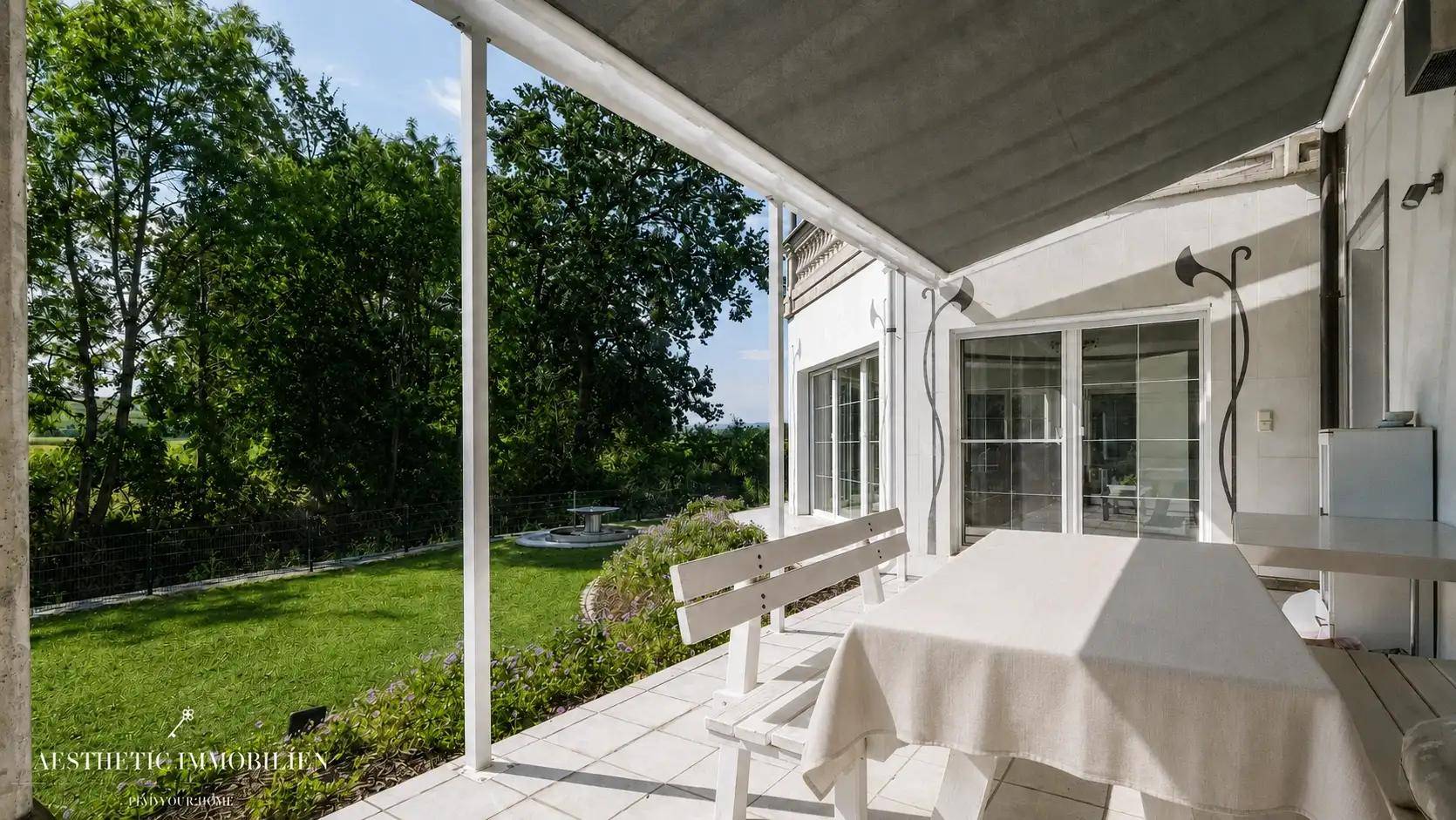 Überdachte Terrasse mit Gartenblick, Sitzgelegenheiten und viel Grün für entspannte Momente.