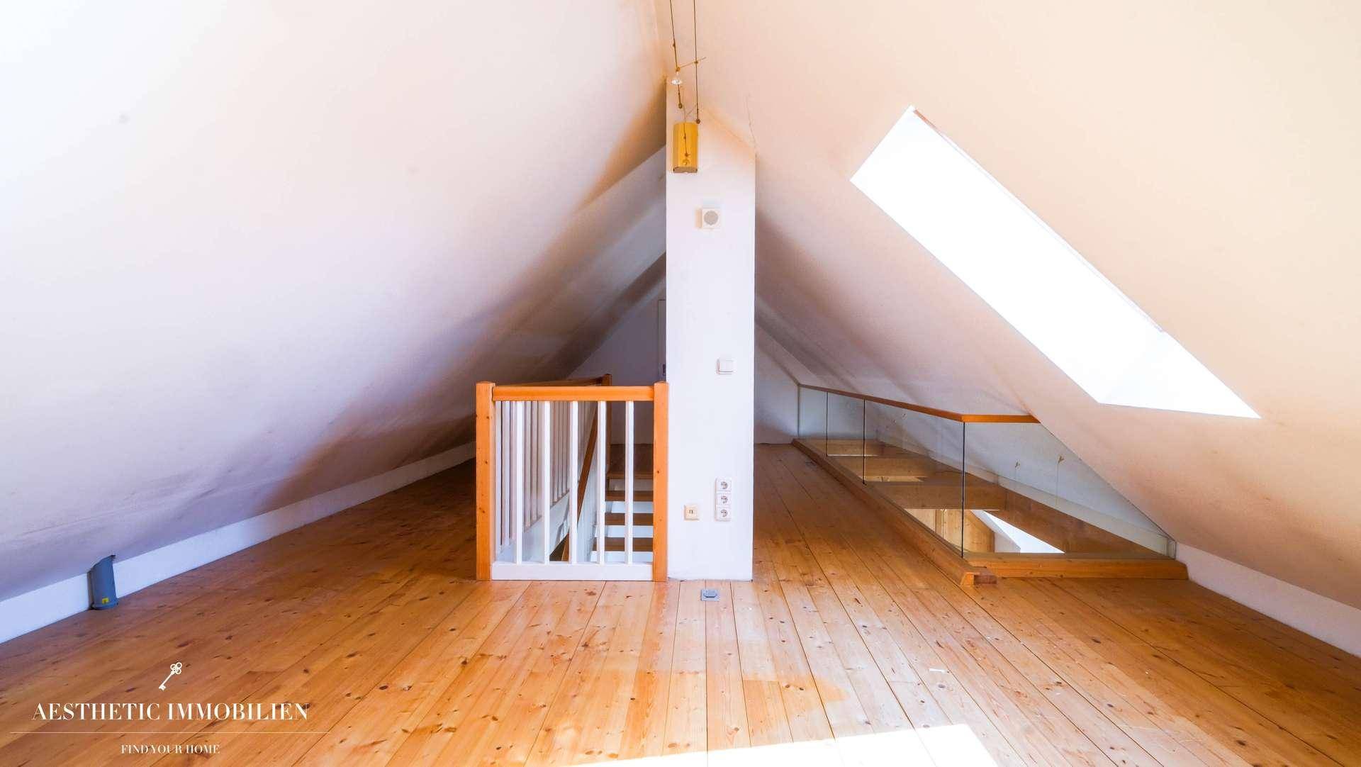Ausgebauter Dachboden mit Holzboden, Dachschrägen und offenem Treppenbereich.