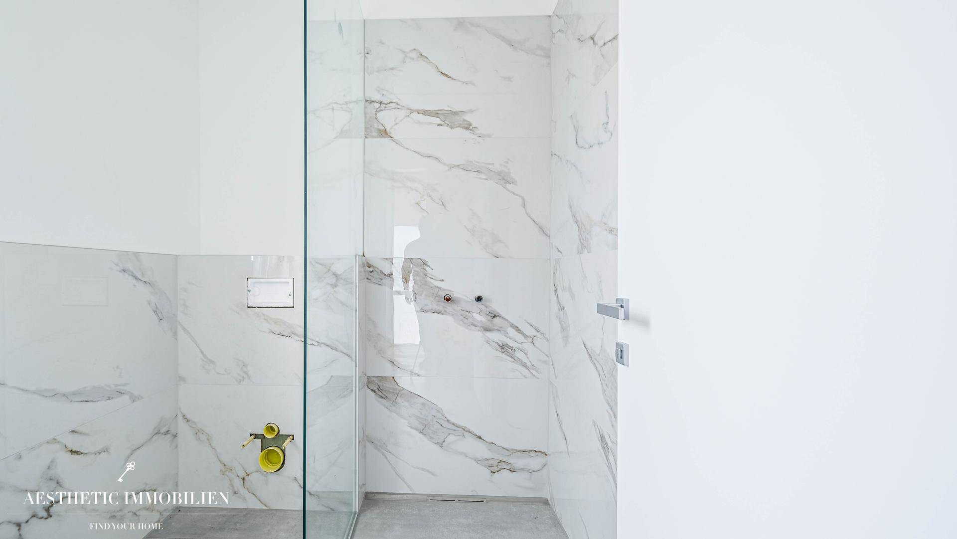 Modernes Badezimmer mit eleganten Marmorfliesen und einer begehbaren Dusche, minimalistisches Design.