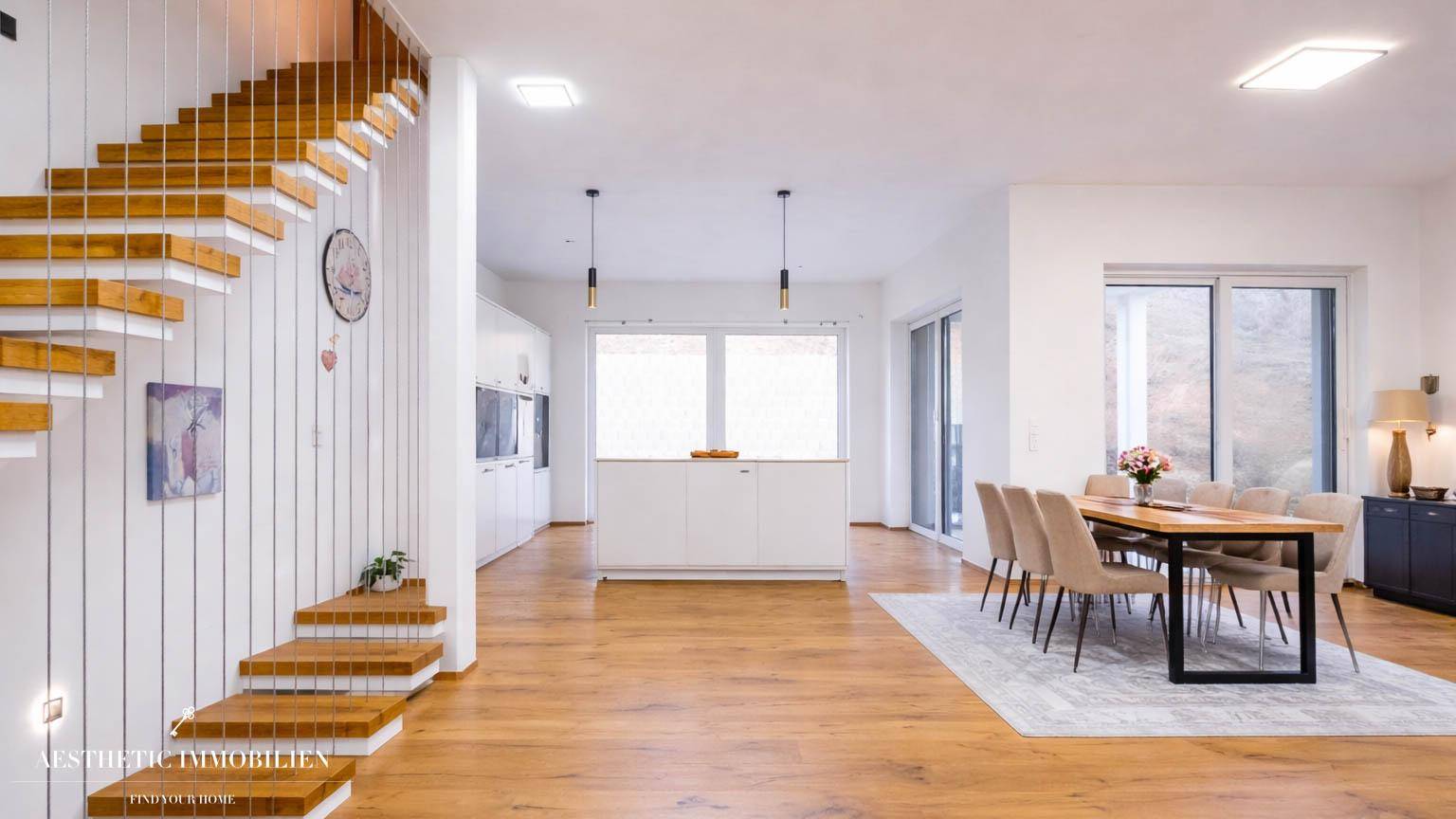 Moderne, offene Küche mit Kochinsel, Essbereich und elegantem Holzboden.