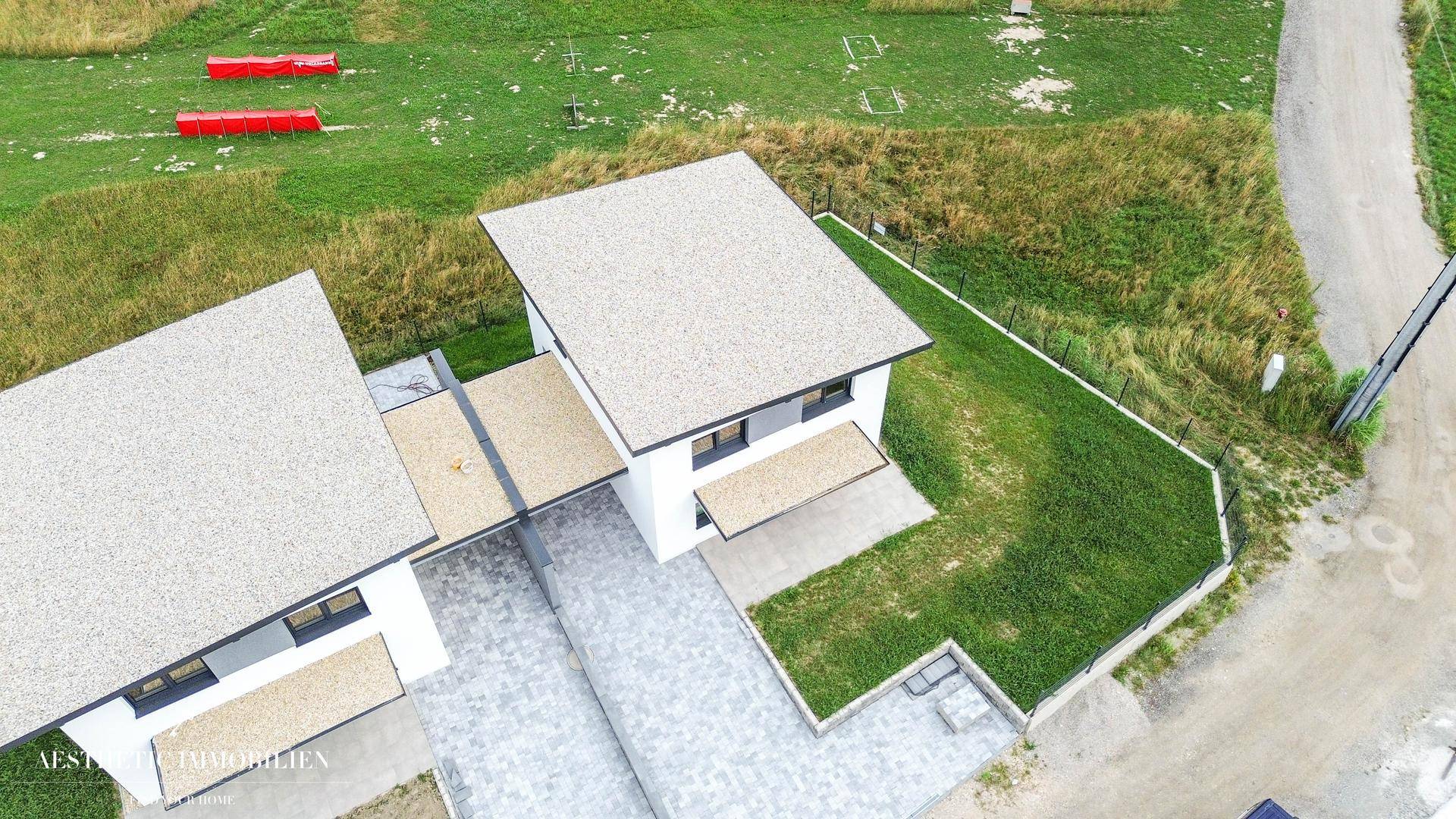 Luftaufnahme des modernen Hauses mit Garten, Zufahrt und umliegender grüner Landschaft.