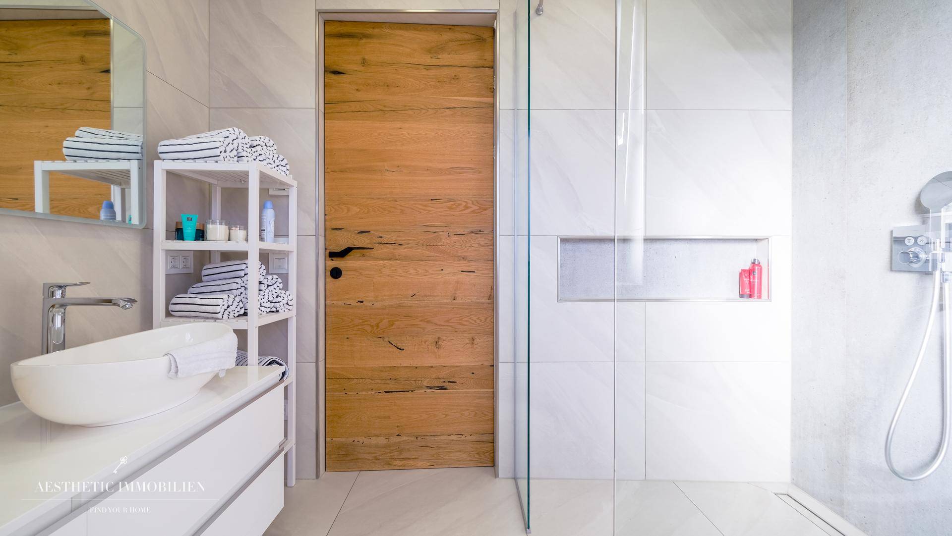 Modernes Badezimmer mit stilvollem Waschbecken, begehbarer Dusche und Holztür.