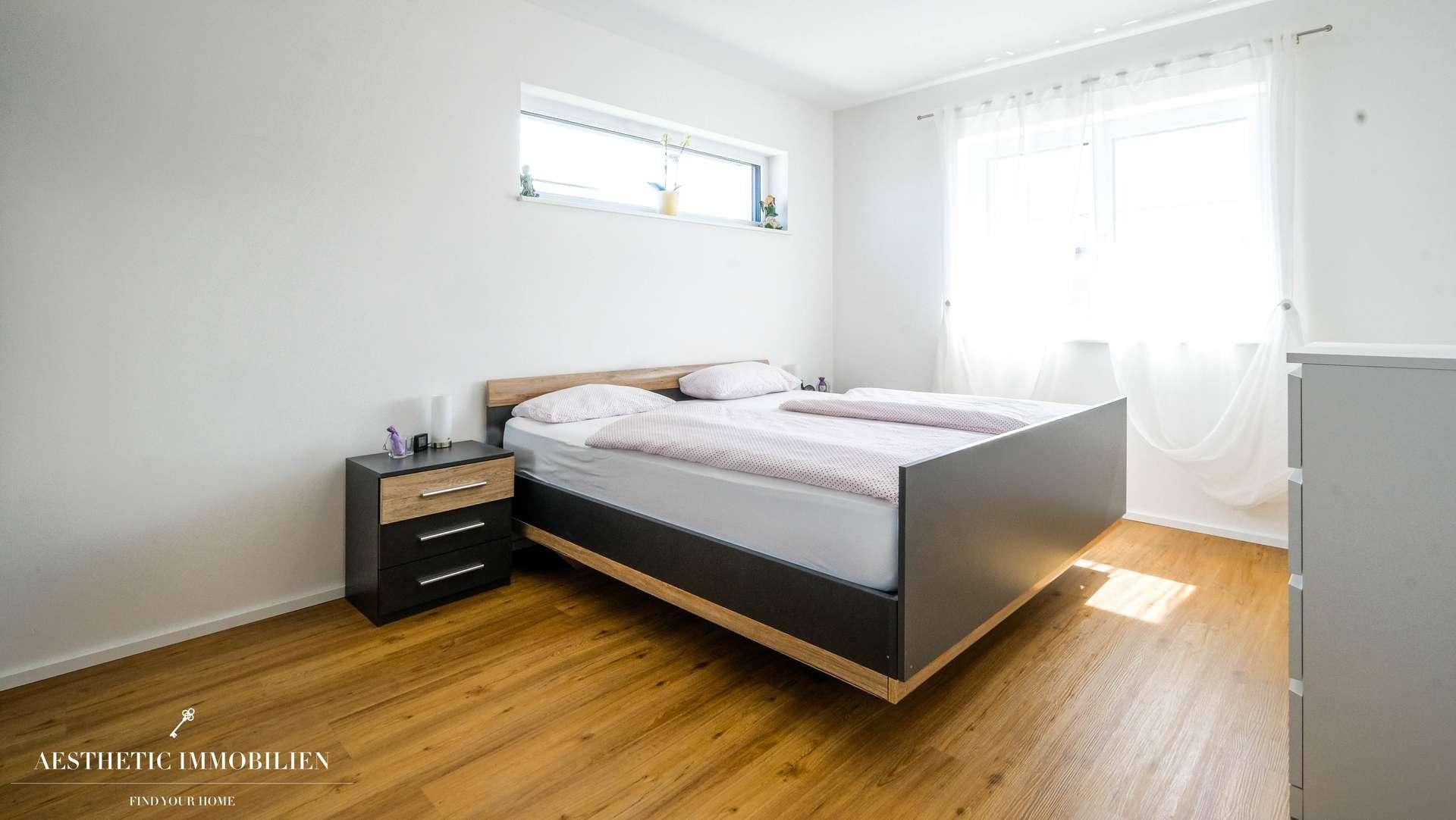Schlafzimmer mit modernem Bett, Nachttischen und hellem Holzfußboden.