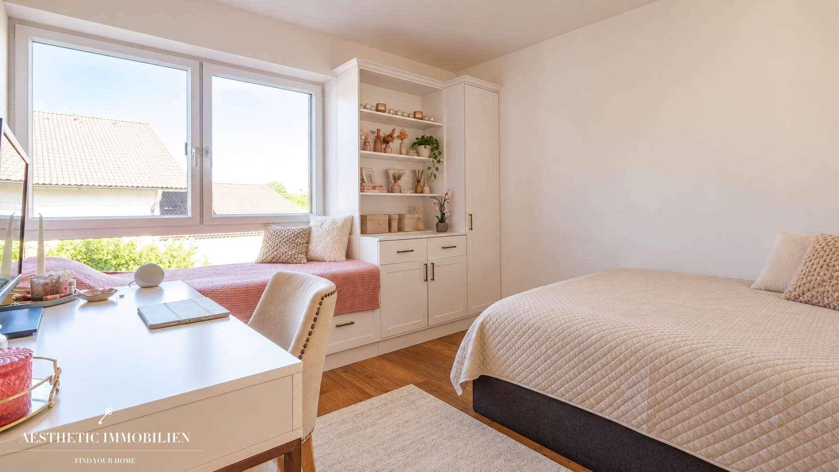Helles Schlafzimmer mit Schreibtisch, Fensterbank und integrierten Regalen.