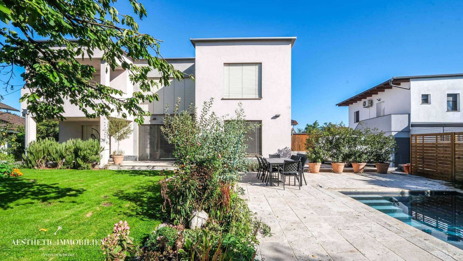 Garten mit Terrasse, Poolbereich und Blick auf die moderne Hausfassade.