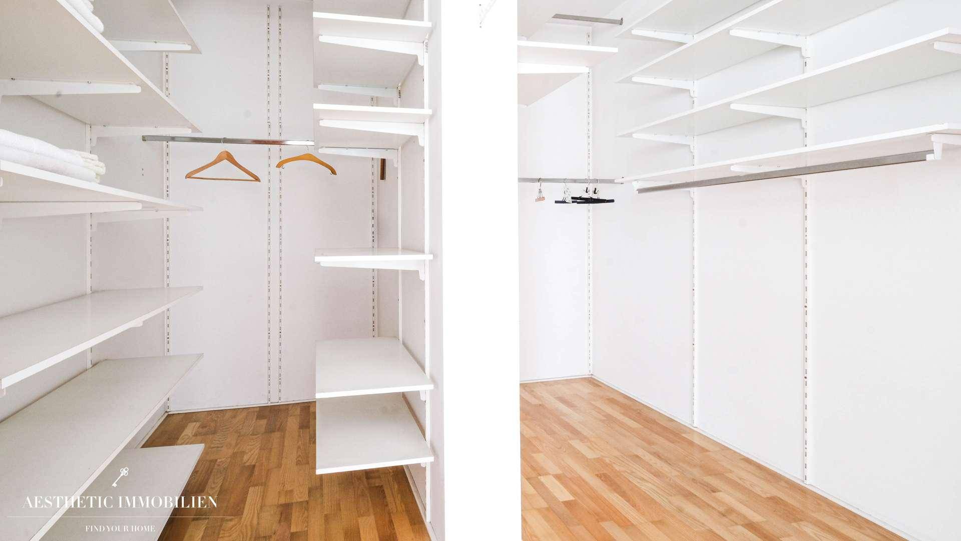Geräumiger begehbarer Kleiderschrank mit vielen Regalen und Holzboden.