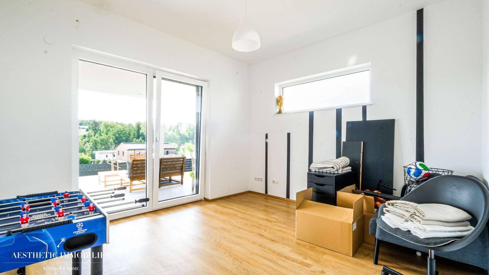Helles Zimmer mit Zugang zur Terrasse, Holzboden und Blick ins Grüne.