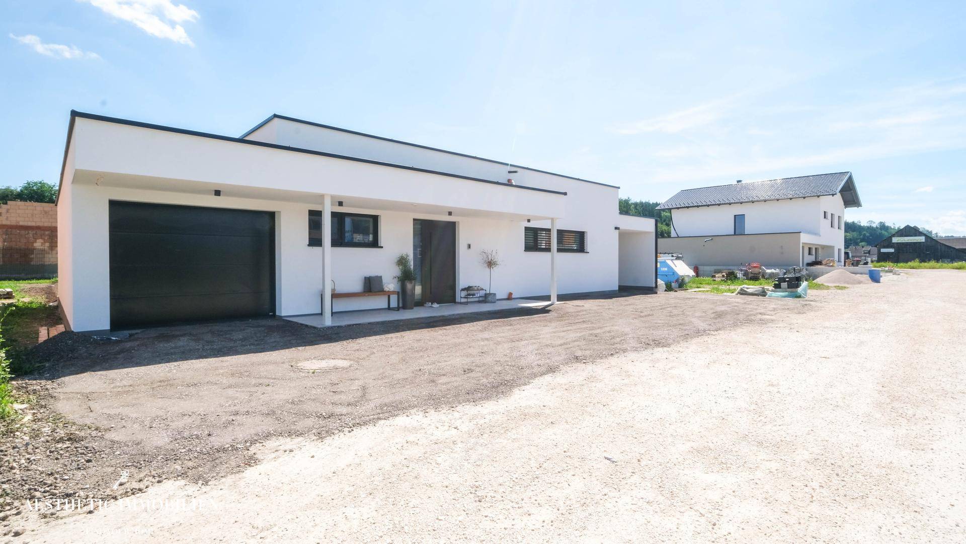 Moderne Hausfassade mit Garage, Carport und großem Vorplatz.