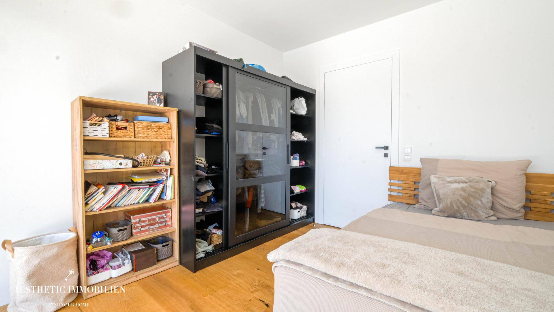 Schlafzimmer mit Holzboden, modernem Bett und praktischen Regalen für Stauraum.
