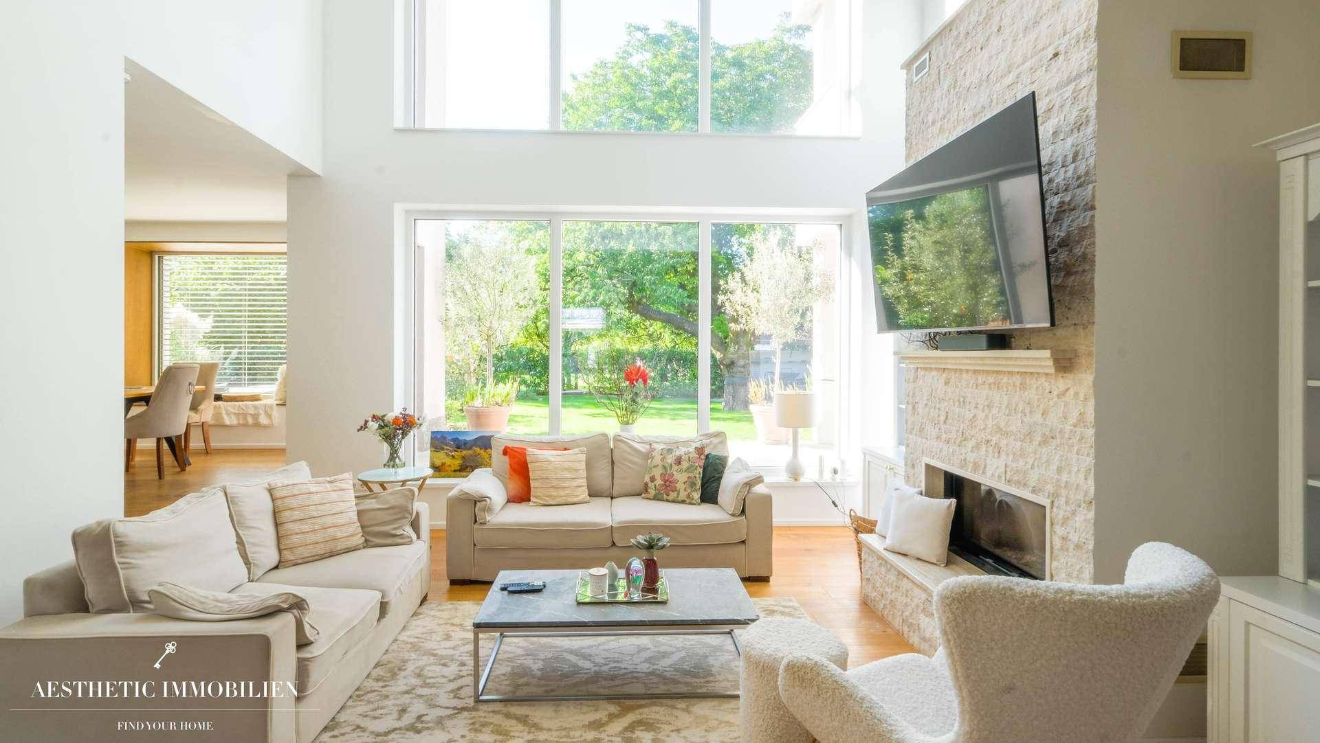 Geräumiges Wohnzimmer mit bequemen Sofas, Kamin und großen Fenstern zum Garten.