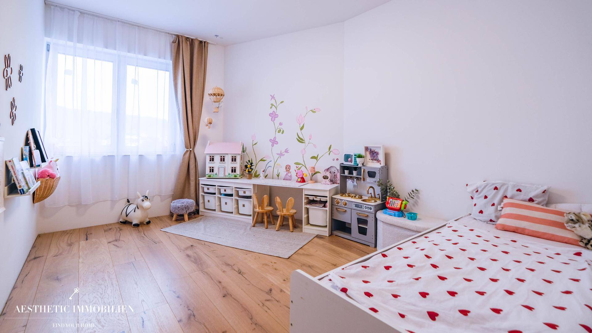 Freundliches Kinderzimmer mit Holzboden, Spielbereich und dekorativen Wandstickern.