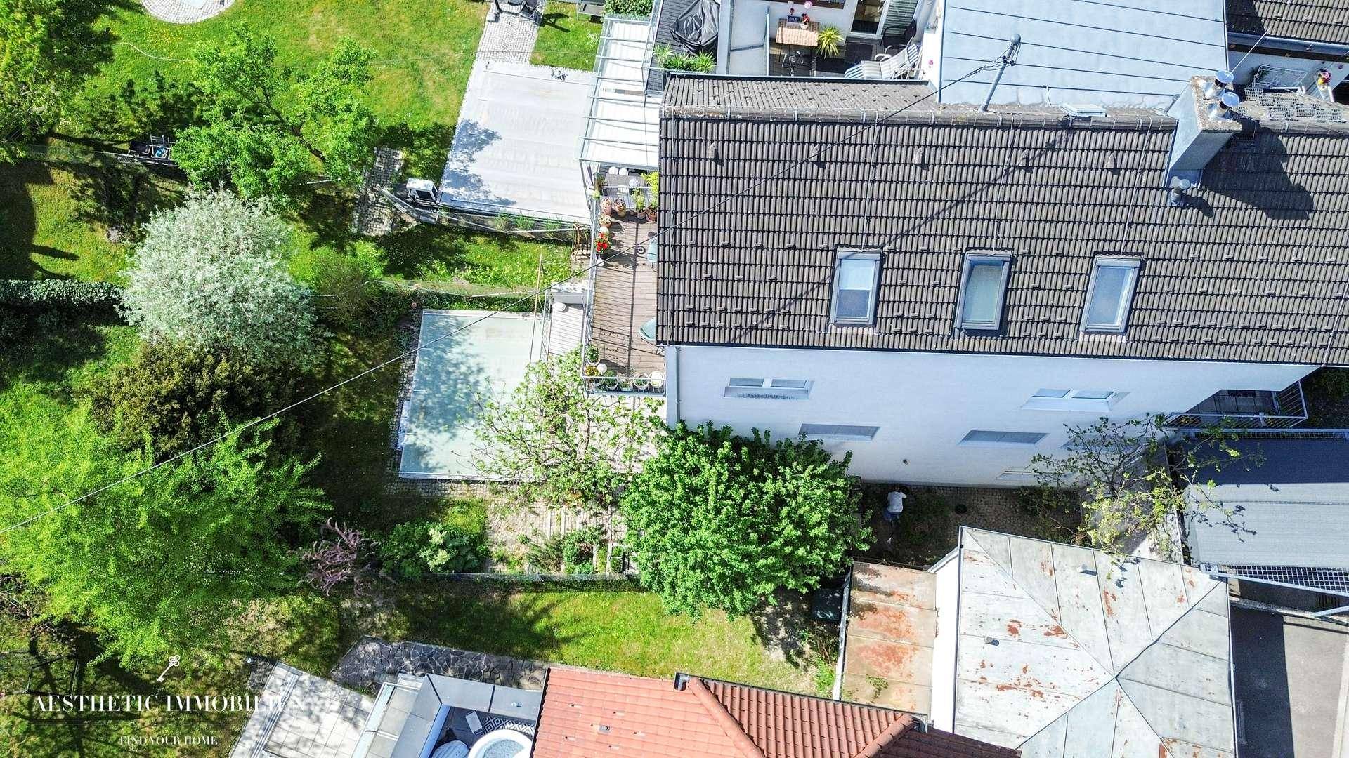 Luftaufnahme eines Hauses mit Ziegeldach, Garten und angrenzenden Gebäuden in grüner Umgebung.