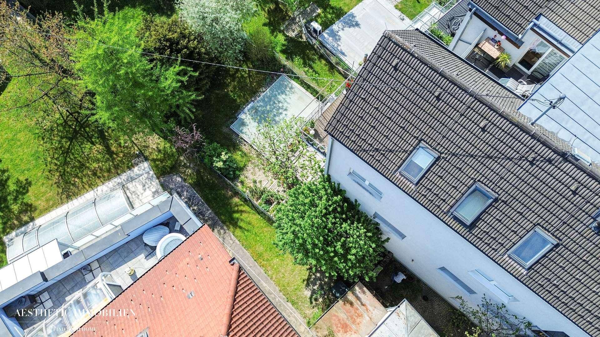 Luftaufnahme eines Hauses mit Ziegeldach, Garten und angrenzenden Grundstücken.